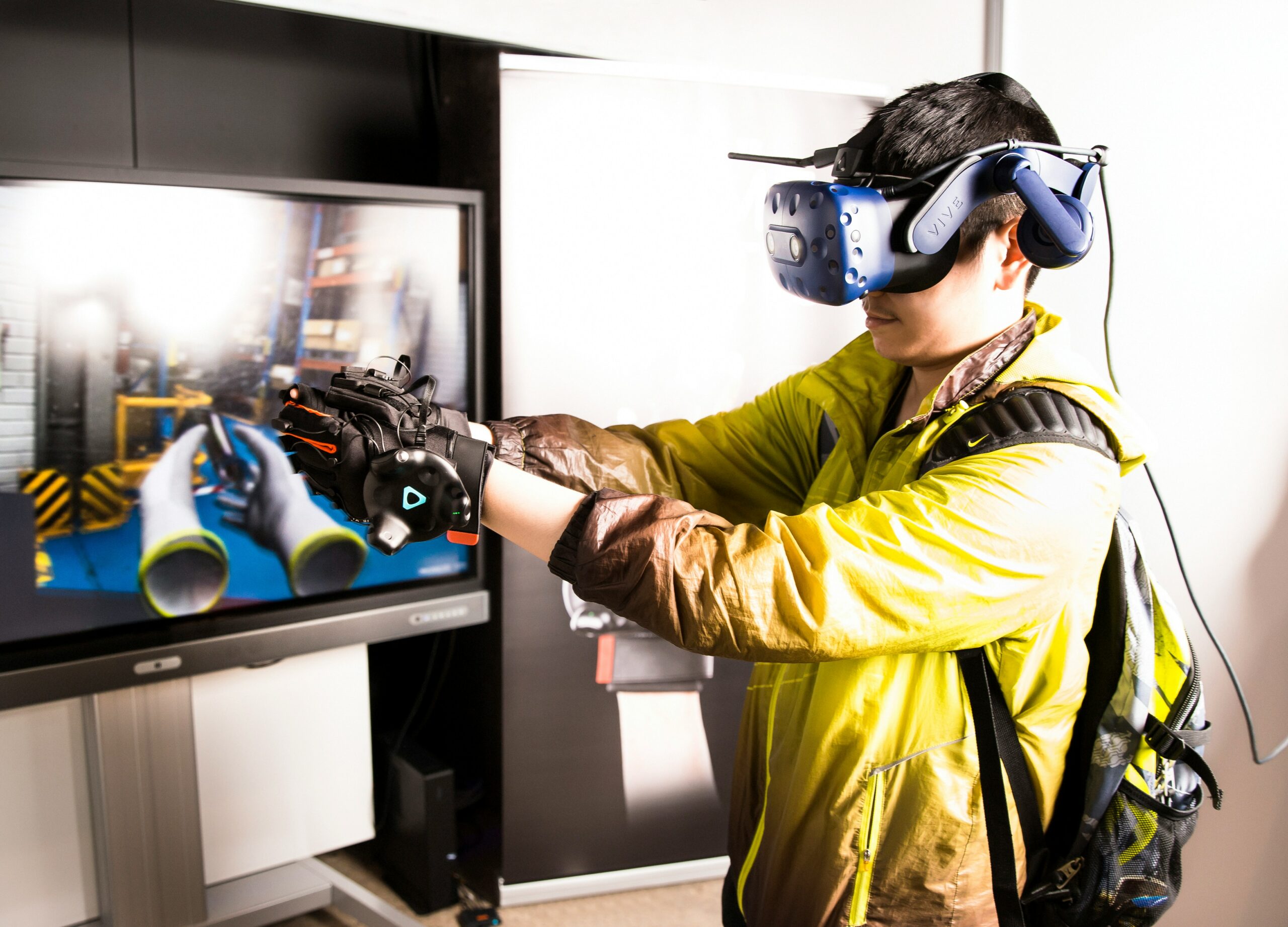 An individual in a yellow jacket holds a virtual reality headset, ready to immerse himself in a virtual career training.